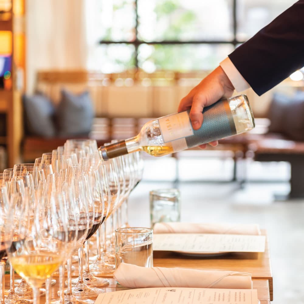 Sommelier Brian Jackson pouring wine as guests sit down
