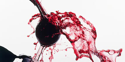 Red wine spilling overfilled glass GettyImages-131985876.jpg