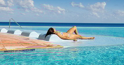 Detail from photo of a young woman by a tropical beach resort hotel infinity pool on the Caribbean Sea