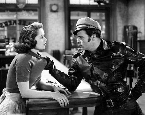 1953 - Marlon Brando in The Wild One 1953 - Marlon Brando in The Wild One - The brimmed hat, leather gloves, thick-soled boots and heavy motorcycle jacket became a kind of uniform for those interested in the more dominant roles in BDSM.