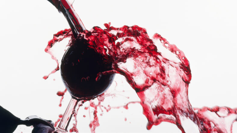 Red wine spilling overfilled glass GettyImages-131985876.jpg